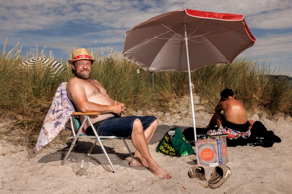 Solhat og solcreme. Morten Arneke er tømrer og har lært at passe på solen i sit job. På stranden i Ishøj er hans hustru ved at brune rygstykkerne inden på lørdag, hvor hun skal til stor fest i fin kjole med bar ryg.  Foto: Jacob Ehrbahn