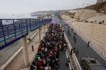 Spansk politi og militær eskorterer en stor gruppe migranter mod Ceutas grænse til Marokko. Ifølge den spanske regering havde knap 50.000 fredag forladt eksklaven igen efter ulovlig indtrængning siden onsdag.   Foto: Jon Nazca/Ritzau Scanpix