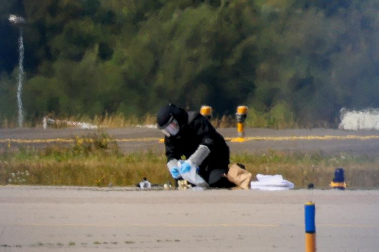 En politibetjent i beskyttelsesudstyr undersøger Leipzig/Halle Lufthavn 5. august efter fundet af en drone nær en landingsbane.  Foto: Axel Schmidt/Ritzau Scanpix