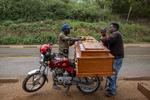 Tømrer Djo Limayo (tv.) laster en kiste på en motorcykel i byen, hvor kistesalget er steget efter ebola-udbruddet. Foto: Arlette Bashizi/Ritzau Scanpix