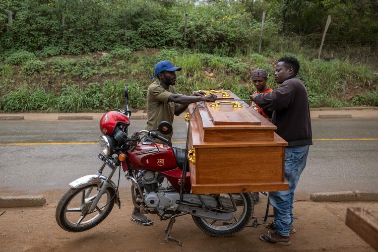 Tømrer Djo Limayo (tv.) laster en kiste på en motorcykel i byen, hvor kistesalget er steget efter ebola-udbruddet. Foto: Arlette Bashizi/Ritzau Scanpix