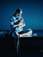 Selv om forestillingen hedder 'Vegetaren', skorter det ikke på kød og blod på scenen. Her sidder den unge kvinde Yeong-hye, spillet af Mette Klakstein, og trøster et grisehoved som en baby. Foto: Rumle Skafte