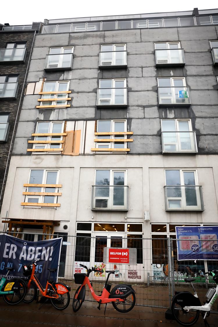 På tredje måned er fortovet foran Rema 1000 spærret af. På facaden ser man længst og øverst til venstre den åbning, hvor altanen hang. Inden viceværten styrtede ned fra den.  Foto: Jens Dresling