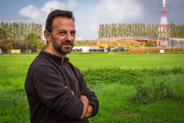 Fra sin have kigger Jeroen Van Reeth direkte over på det område, hvor den forurenede jord samles og transporteres via den specialbyggede røde bro over til fabrikken 3M.  Foto: Joseph Backes