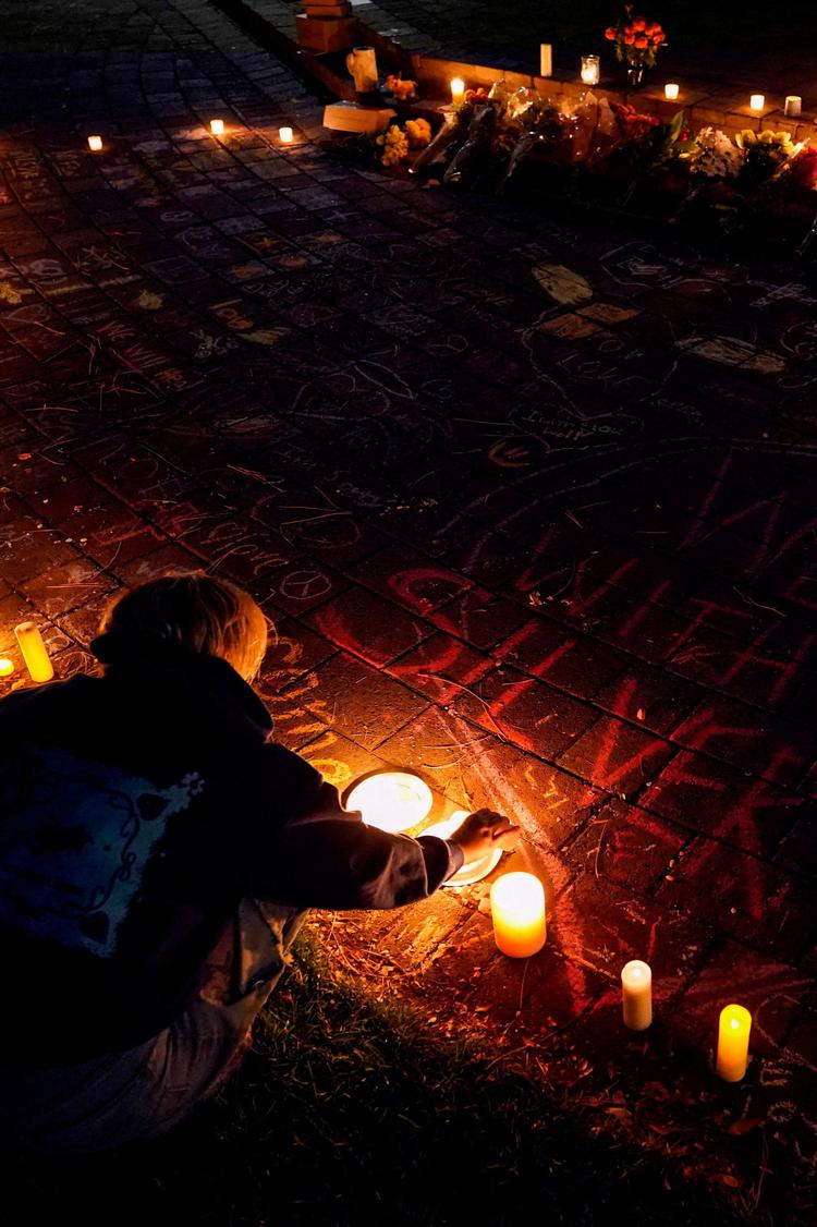 En kvinde tænder et lys under en mindehøjtidelighed i Drake Park i Bend, Oregon, for ofrene. Foto: David Ryder/Ritzau Scanpix