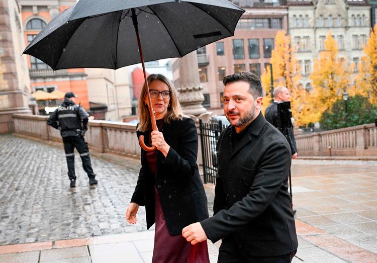 Ukraines præsident Volodymyr Zelenskyj søger ly under en norsk paraply, da han ankommer til Stortinget på besøg dagen efter fredsforhandlinger med USA. Nu vil EU også have Norge og andre parter uden for EU til at sikre Ukraine økonomisk ly fremover.  Foto: Jonathan Nackstrand/Ritzau Scanpix