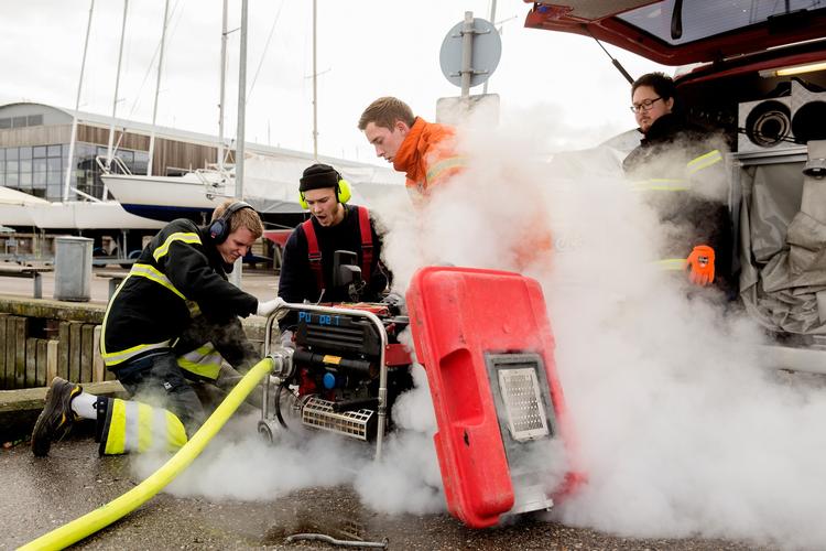 Ricky Vedsegaard (tv) hjælper to andre ildfugle med få gang i kompressoren. Medinstruktør Niels Oluf med de gule hørebøffer ser på. 

Øvelse på havnen i Roskilde. 