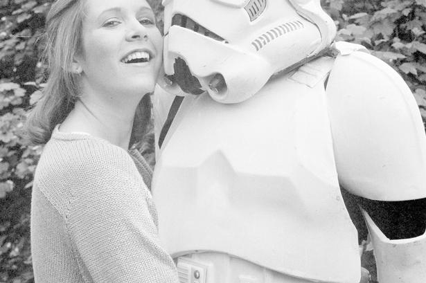 Carrie Fisher giver en krammer til en uidenticeret person, klædt ud som Storm Trooper, i 1980.  