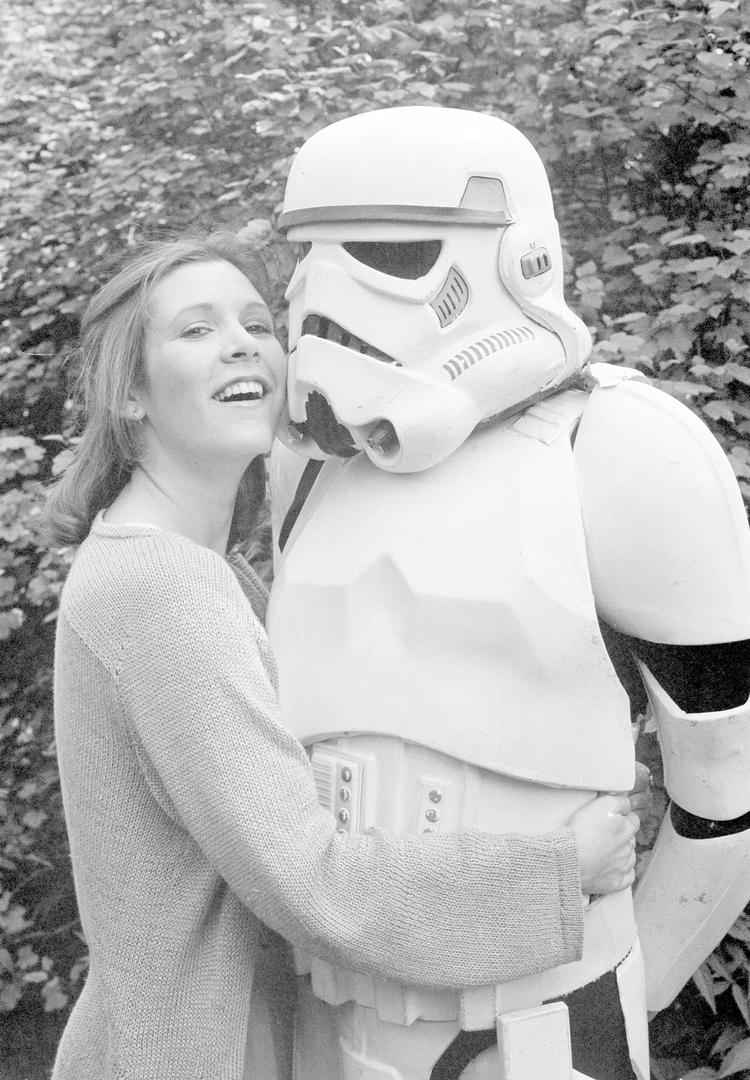Carrie Fisher giver en krammer til en uidenticeret person, klædt ud som Storm Trooper, i 1980.  