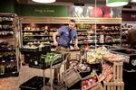 Max Thomsen sætter bananer, gulerødder og spidskål op til udstilling i SuperBrugsen i Stenlille.  
