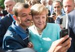 Tre dage efter, at den syriske flygtning kom til asylcenteret her i Spandau, kom Angela Merkel på besøg og lod flygtninge tage selfie  - her er hun sammen med en anden mand samme dag.-  Foto: Bernd von Jutrczenka/dpa via AP) 