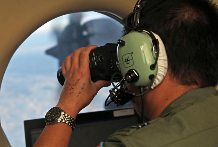En ansat ved det australske luftvåben spejder fra et fly ud over Det Indiske Ocean for at lede efter MH370.  
