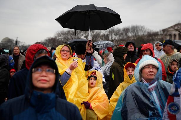 Tilskuere venter i regnen i National Mall - det store grønne parkområde foran Capitol Hill i Washington i dag. 