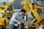 En fabriksarbejder tester robotarme i Zhejiang.
 