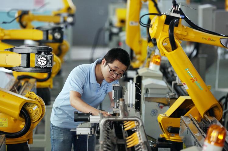 En fabriksarbejder tester robotarme i Zhejiang.
 