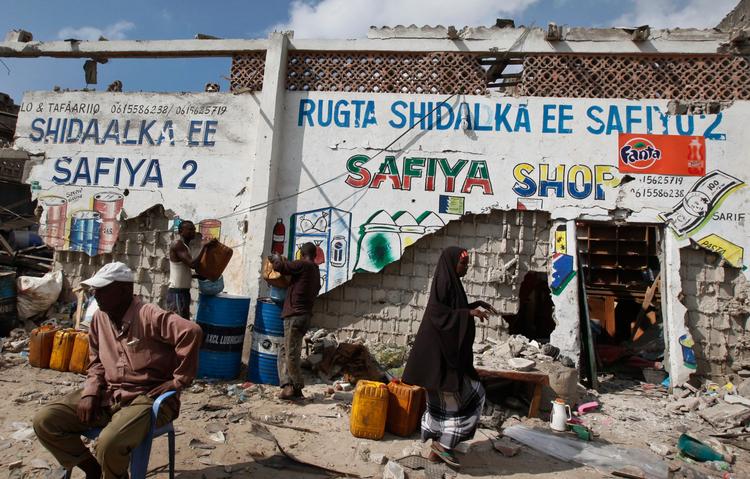 En somalisk mand sidder ved siden af sin ødelagte forretning, efter en selvmordsterrorist har angrebet en politistation i nærheden. 