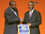 På dette foto fra 2006 ses Amos Adamu (tv.), da han hilser på den daværende sydafrikanske præsident Thabo Mbeki ved åbningen af en VM-workshop i Cape Town.
 