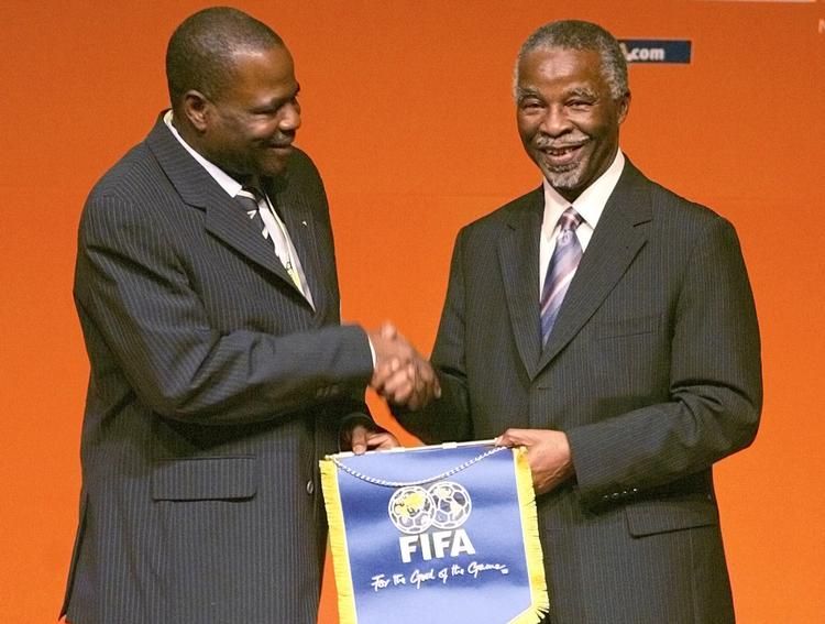 På dette foto fra 2006 ses Amos Adamu (tv.), da han hilser på den daværende sydafrikanske præsident Thabo Mbeki ved åbningen af en VM-workshop i Cape Town.
 