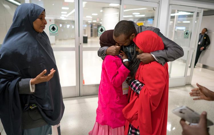 Ismail Issack omfavner sine børn, 11-årige Miski Shalle og 14-årige Muzamil Shalle, 14, da de mødes for første gang i syv år i John F. Kennedy Lufthavnen New York i går. Familien skulle oprindeligt have været genforenet tidligere på året, men det blev forpurret af Donald Trumps første indrejseforbud.  
