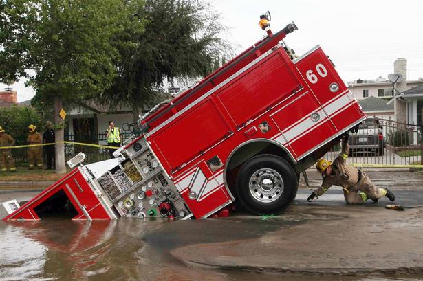 En brandmand kigger nærmere på skaderne på en brandbil, der er kørt i etsinkhole Valley Village, Los Angeles. 8. september 2009. 