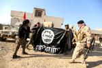 Islamisk Stat er hårdt presset i Syrien og Irak. Her er irakiske soldater fotograferet med et erobret IS-flag i november.  