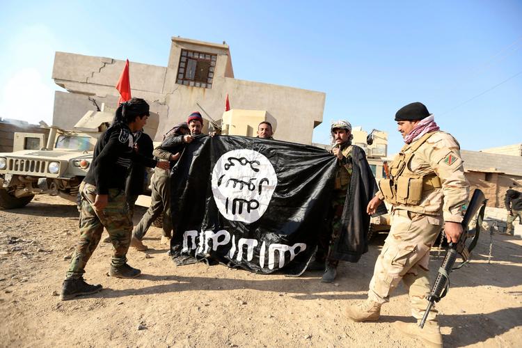 Islamisk Stat er hårdt presset i Syrien og Irak. Her er irakiske soldater fotograferet med et erobret IS-flag i november.  