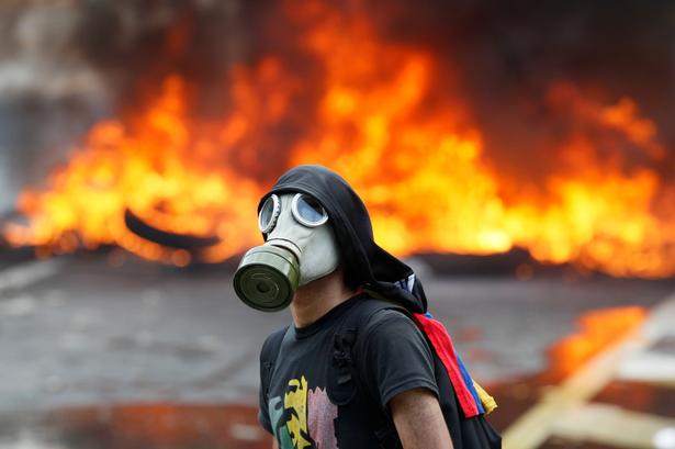 Mindst 24 mennesker er dræbt og mange sårede under voldsomme demonstrationer i Venezuela. Her en demonstrant foran en brændende barrikade i Caracas, Venezuela.  