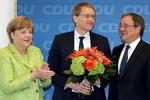 Merkels mand i midten. Daniel Günther belønnes med blomster fra forbundskansleren (tv), da han besøgte hovedkvarteret i Berlin i går. Til højre næste mand på affyringsrampen - kandidaten for CDU i Nordrhein-Westfalen, Armin Laschet. (AP Photo/Michael Sohn) 