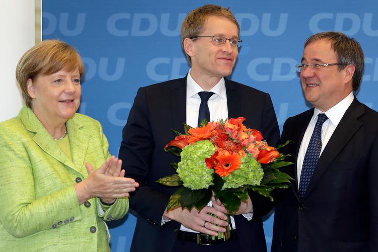 Merkels mand i midten. Daniel Günther belønnes med blomster fra forbundskansleren (tv), da han besøgte hovedkvarteret i Berlin i går. Til højre næste mand på affyringsrampen - kandidaten for CDU i Nordrhein-Westfalen, Armin Laschet. (AP Photo/Michael Sohn) 