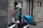 Et mand køber varer i en af de købmandsbutikker i centrum af Beijing, der har fået facaden muret til, så der nu kun er et lille vindue. 