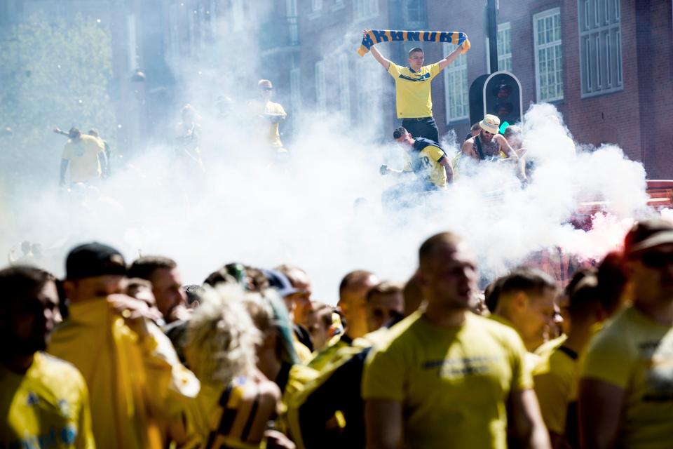 I en sky af røg fra romerlys bliver slagsangene dirigeret fra taget af busser, som kører midt i Brøndby-tilhængernes optog ud til Parken. 