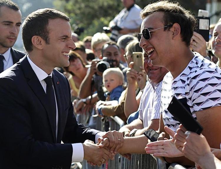 Macron hilser på vælgerne efter at have afgivet sin stemme. 