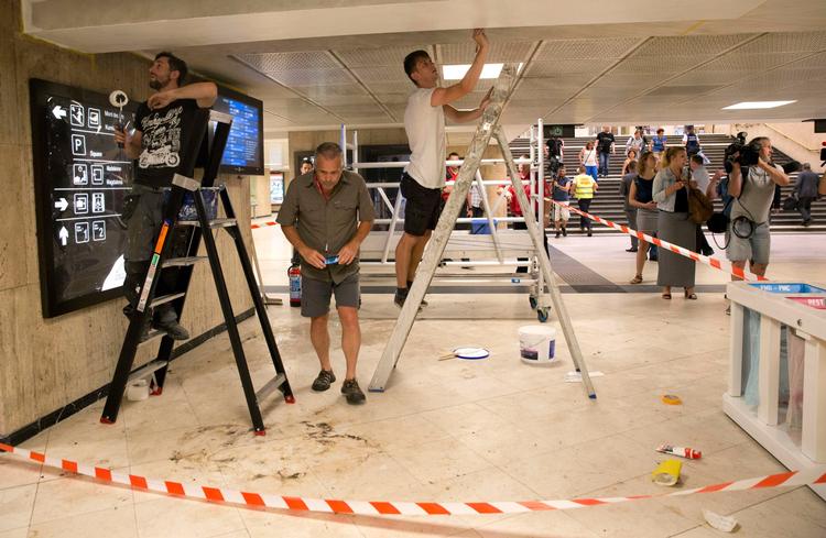 En efterforsker taget er billede og en maler udbedrer skaderne efter gårsdagens terrorangreb i Bruxelles.  