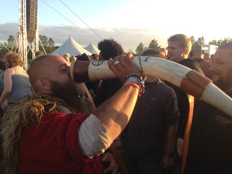 Nilas Holst, der er fuldt klædt som viking, drikker mjød fra et meter langt drikkehorn.  