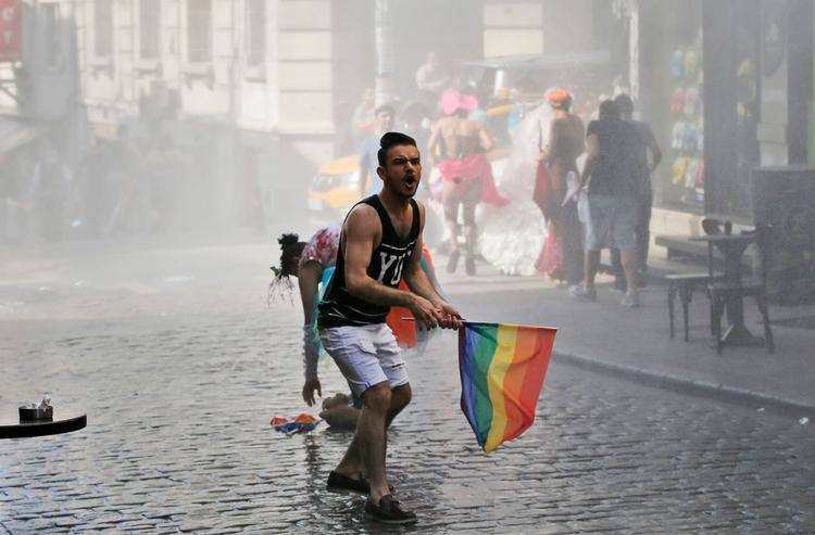 En deltager i Gay Priden søndag i Istanbul forsøger at trodse politiets hårdhændede fremfærd. 