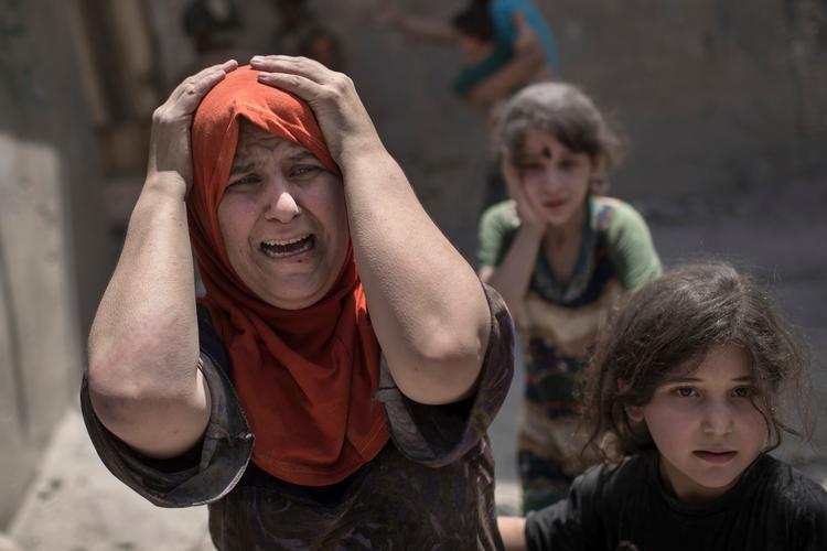 En kvinde skriger, mens hun flygter med sin familie gennem en sønderskudt gade i Mosul tidligere i dag.  
