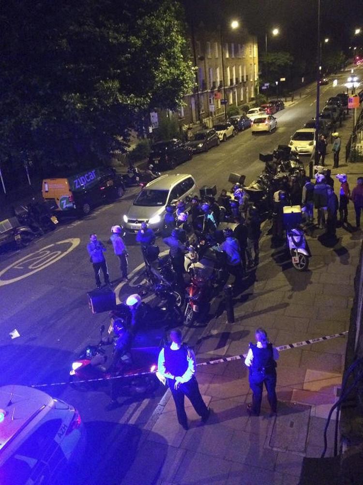 Politiet i London er samlet ved gerningsstedet efter et angreb torsdag, hvor en 32-årig mand fik kastet en skadelig substans i ansigtet af gerningsmænd, der stjal hans knallert - og kørte væk. Foto: Sarah Cobbold via AP 