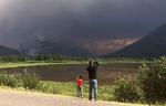 Turister i Banff National Park tager billeder af skovbranden i de nærliggende bakkedrag  