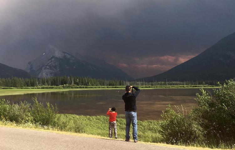 Turister i Banff National Park tager billeder af skovbranden i de nærliggende bakkedrag  