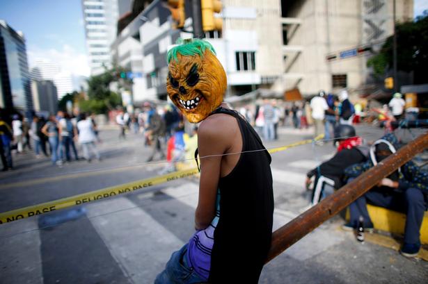 Flere af demonstranterne bærer masker. Her hviler demonstranter bag en af deres mange barrikader på valgdagen. 

Mange tomme valgsteder søndag peger på, at mange valgte en stille protest, ved at blive væk fra stemmeurnerne.  