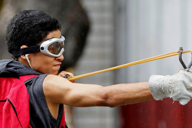 Da demonstranterne ikke har våben, tyer nogle til at lave deres egne. Her skyder en demonstrant med en hjemmelavet slangebøsse, under den 48-timer lange generalstrejke, der begyndte onsdag og lammede flere sektorer i landet.  