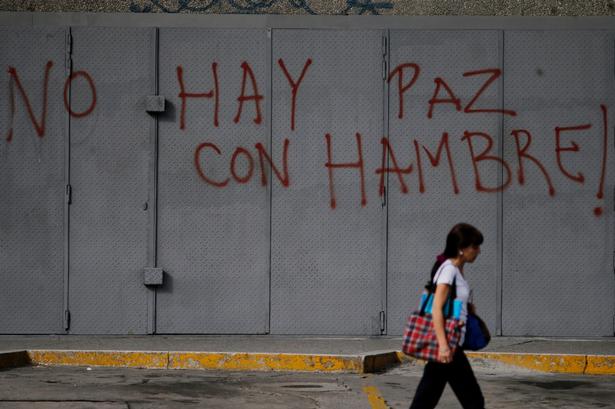 Venezuela er i forvejen i økonomisk krise, og befolkningen mangler både mad og medicin.  Her går en fodgænger forbi en væg, der er spraymalet med ordene »Der er ingen fred, når der er sult«.
Det er ikke muligt, at vide, præcis hvordan landets økonomi ser ud, da regeringen ikke vil offentliggøre nøgletal.  