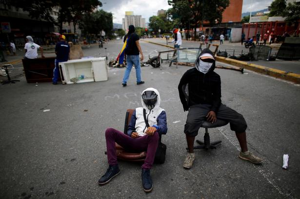 Mindst 10 mennesker er meldt dræbt siden lørdag, men oppositionen hævder, at det er flere. Her holder maskerede demonstranter vagt ved en barrikade tre dage før søndagens afstemning. Demonstranterne bruger blandt andet møbler og fyldte skraldesække til at afspærre veje. 