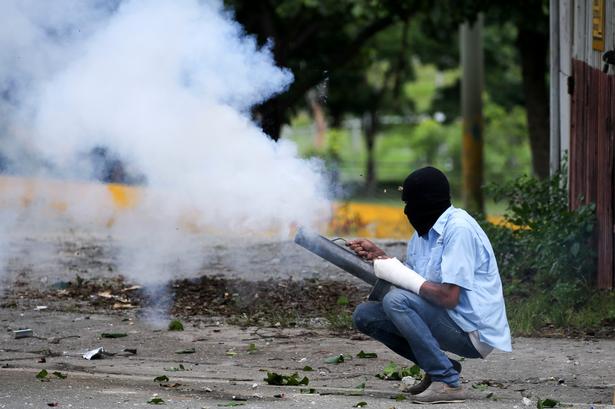 En demonstrant bruger en morter til at skyde fyrværkeri mod sikkerhedsstyrker.
Andre bøjer hule jernrør, som kan bruges som skydevåben. 