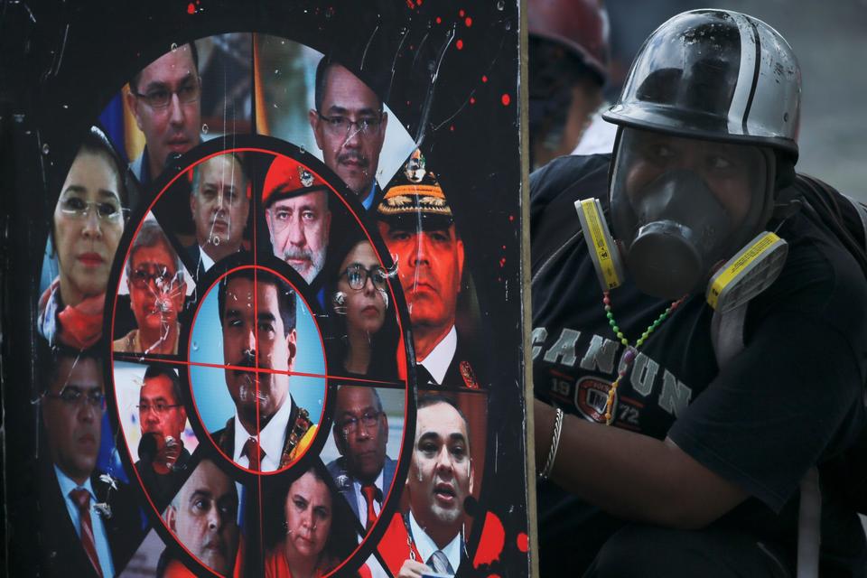 Nicolas Maduro har tidligt i dag,  mandag, erklæret sig for vinder af valget af en nationalforsamling. Oppositionen, der boykottede afstemningen, opfordrer nu til nye demonstrationer.
Her holder en demonstrant et hjemmelavet skjold under et sammenstød med sikkerhedsstyrkerne ved en demonstration en uge før valget.
På skjoldet ses billeder af Maduro og hans embedsmænd.   