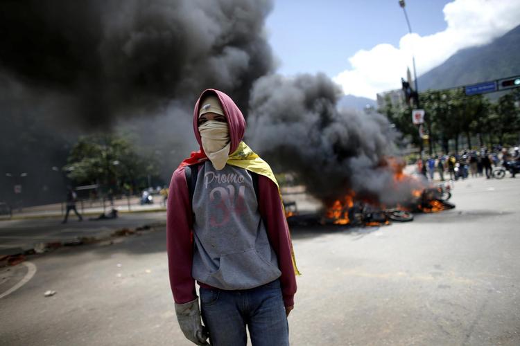 En demonstrant vandrer rundt i hovedstaden Caracas, mens motorcykler brænder. Betjente blev set kaste motorcykler på bålet, efter en eksplosion, hvor politiets motorcykler brændte. 