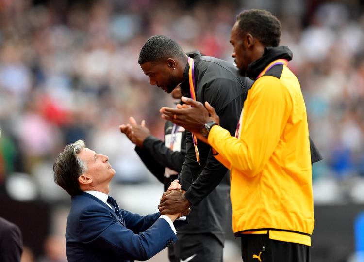 IAAF's præsident Sebastian Coe overrækker Justin Gatlin VM-guldmedaljen, mens Usain Bolt klapper anerkendende af sin overmand.
   