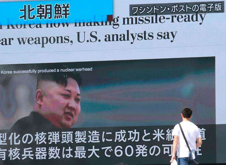 En japansk mand passerer en stor tv-skærm, der viser nordkoreas leder, Kim Jong Un, og fortæller om landets angrebstrusler.  