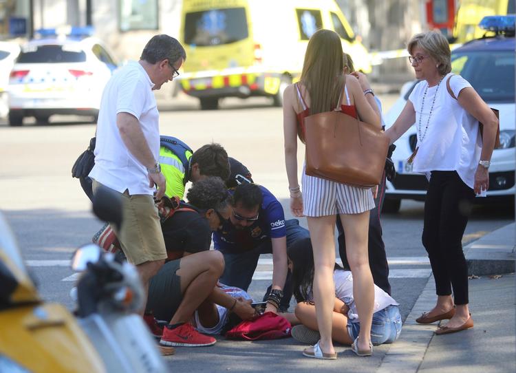 En såret bliver behandlet på gaden i Barcelona, efter en hvid varevogn torpederede og sårede 100 personer på hovedgaden La Rambla i et terrorangreb. 13 er dræbt.  Oriol Duran/AP