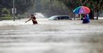 Moses Juarez (tv.) og Anselmo Padilla (th.) vader gennem de oversvømmede gader i Houston, Texas, hvor den tropiske storm Harvey hærger. 